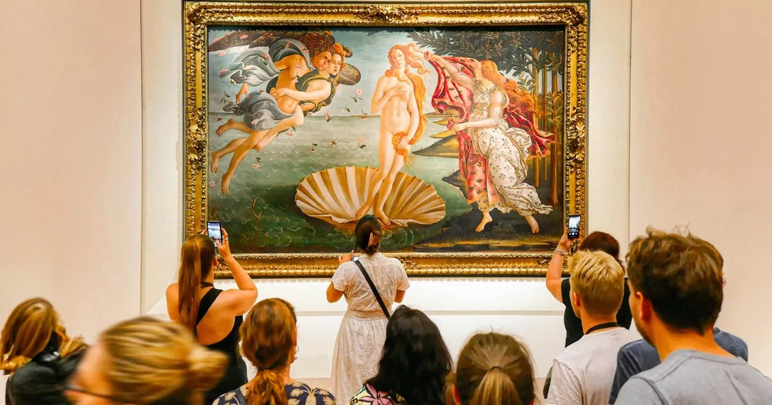 Visitors holding up phones in front of Botticelli's Birth of Venus in a gold frame